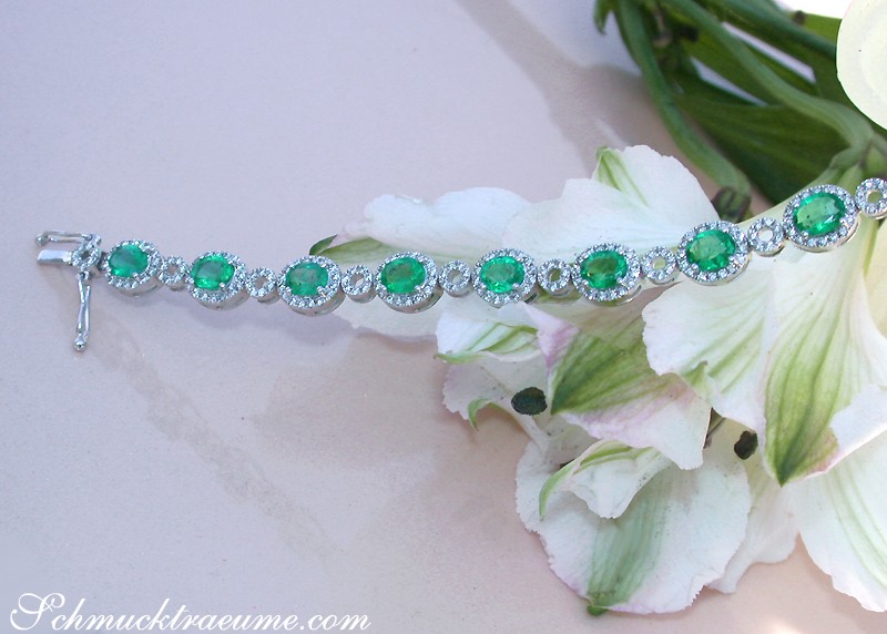 Smaragd-Armband mit Brillanten auf weißem Hintergrund, Detailaufnahme, Blumen im Hintergrund.