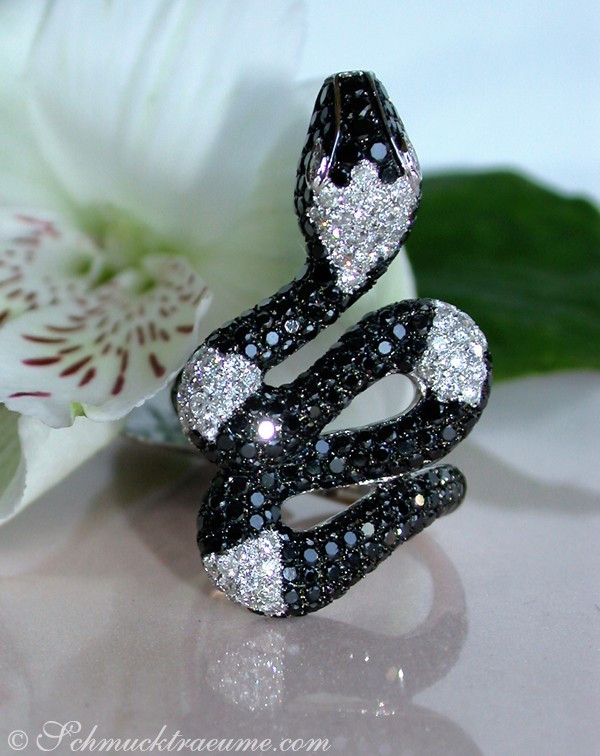 Schwarz-schimmernder Diamant-Ring im Schlangen-Stil auf Blume, Detailaufnahme.
