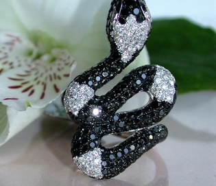 Schwarz-schimmernder Diamant-Ring im Schlangen-Stil auf Blume, Detailaufnahme.