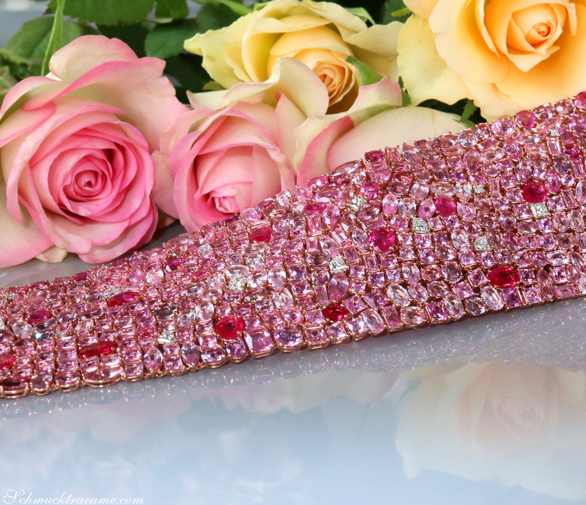 Pinkes Saphir-Armband mit 485 Steinen, 115,07 ct., auf glänzender Oberfläche, Rosen im Hintergrund.