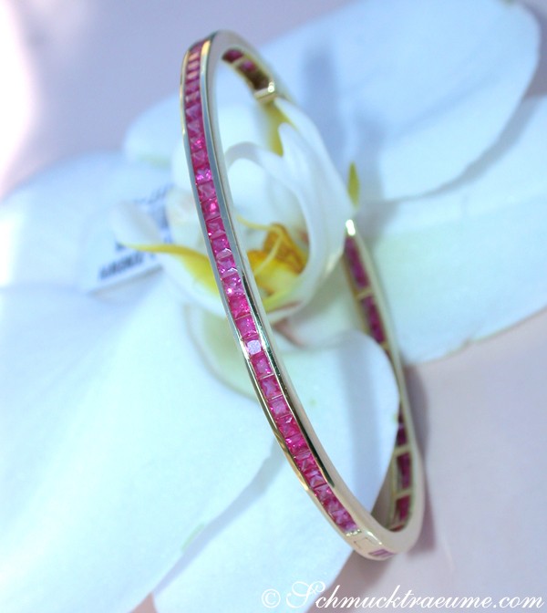 Goldene Bangle mit Rubinen auf Orchideenblüte