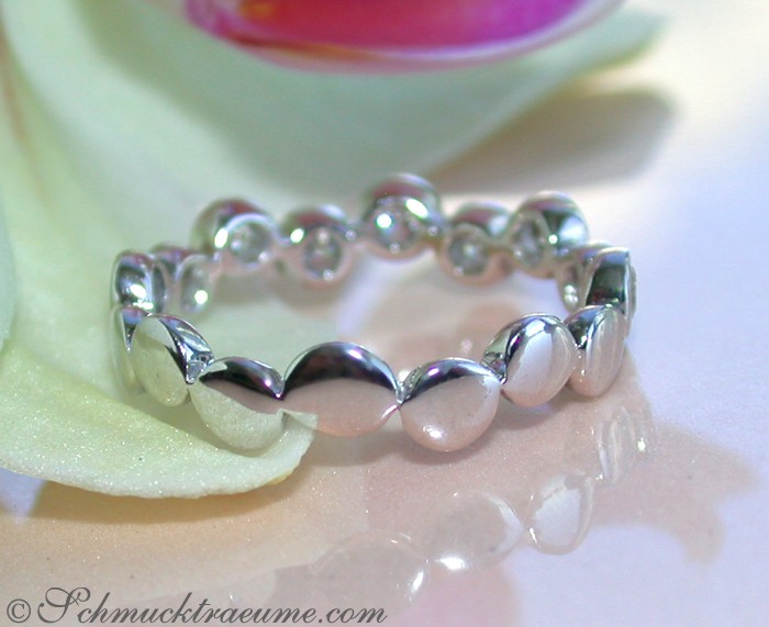 Edler Diamanten Memory Ring in Weißgold, Detailaufnahme, glänzende Perlen, rosafarbene Blüte im Hintergrund