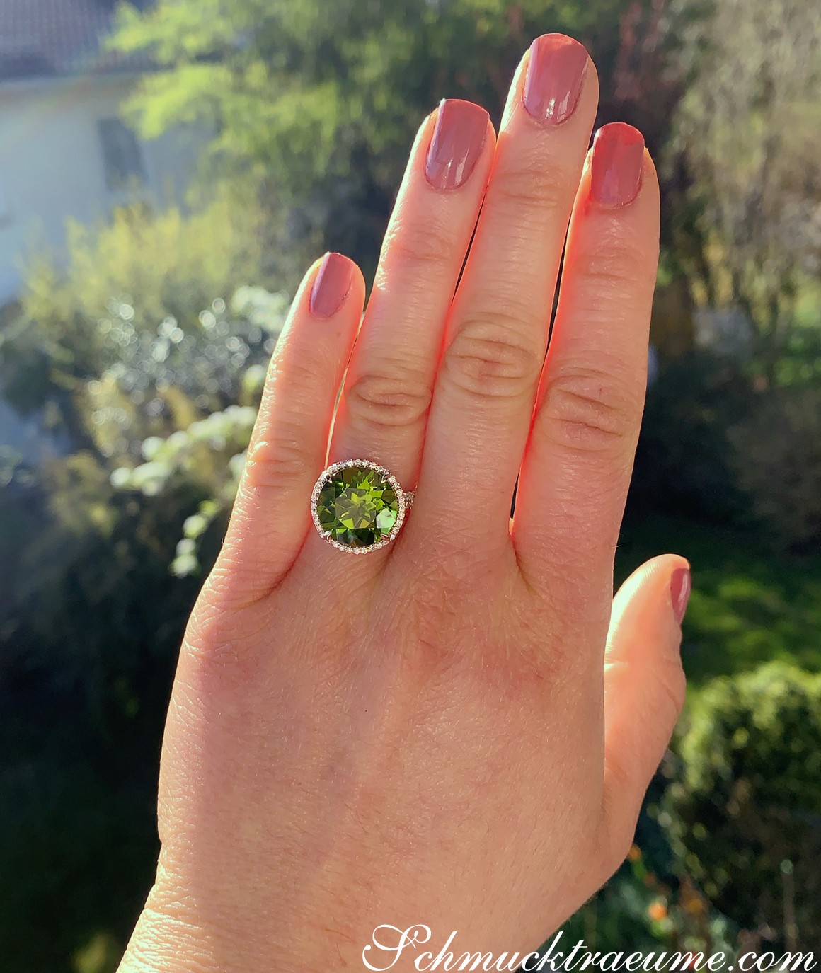 Peridot-Ring mit Brillanten auf Hand, Detailaufnahme, strahlendes Moosgrün, Gelbgold 750