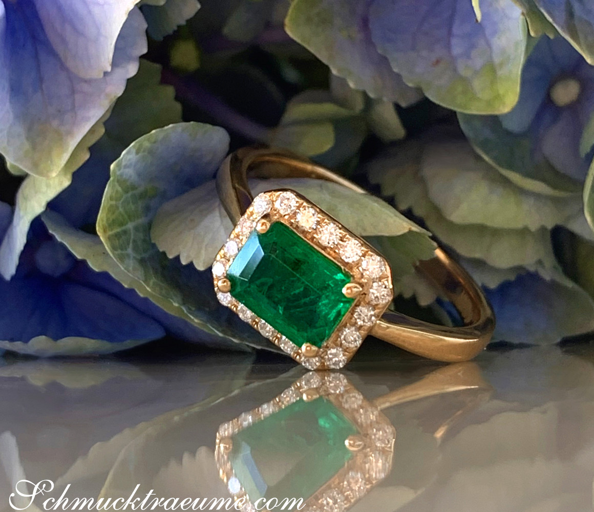 Goldener Smaragd-Ring mit Brillanten auf Blütenhintergrund