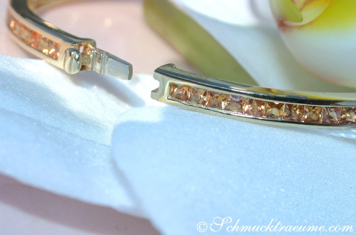 Goldener Armband mit orangefarbenen Saphiren auf weißem Hintergrund