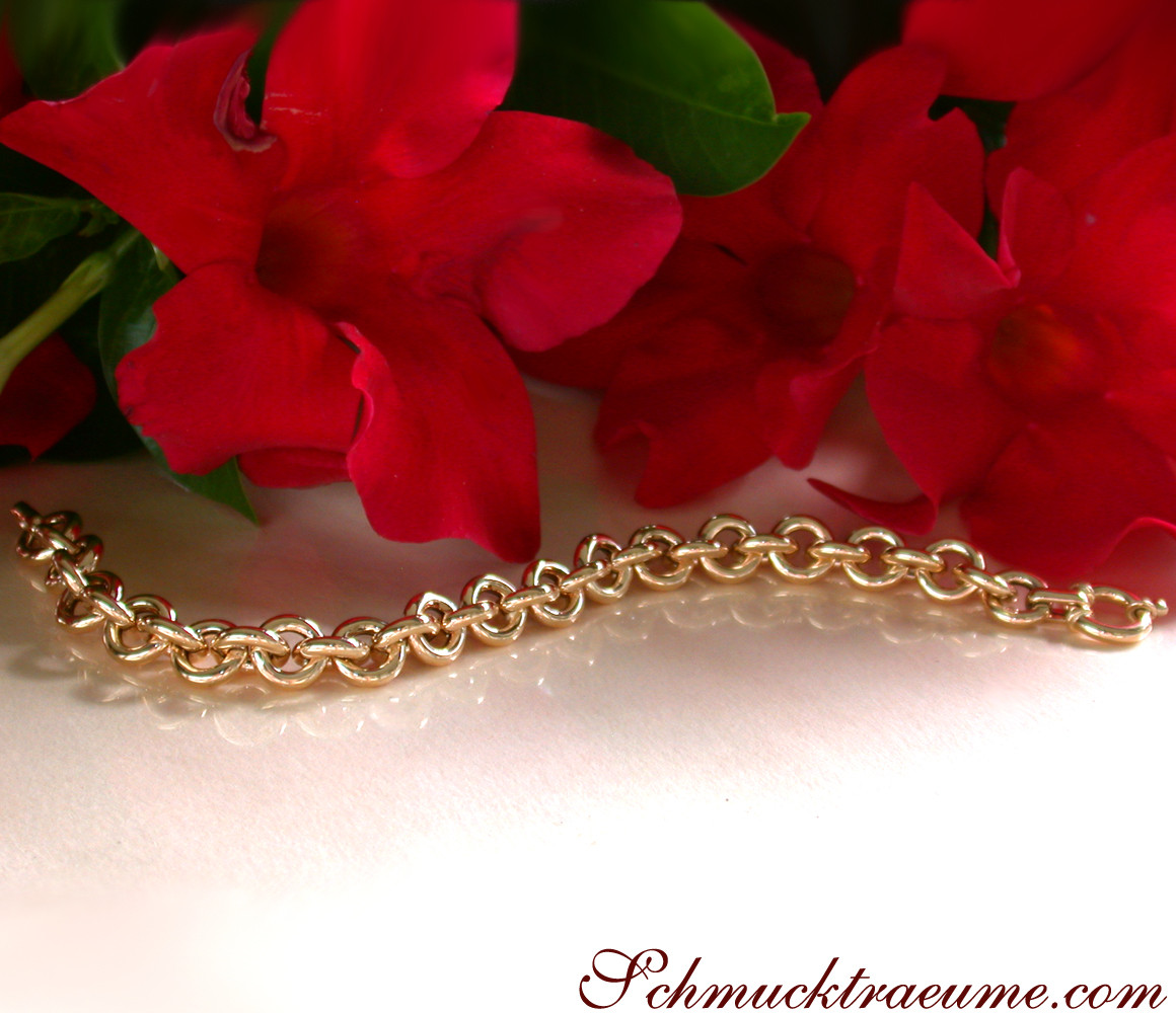 Goldenes Gliederarmband mit strahlenden Ringen auf Blumenhintergrund