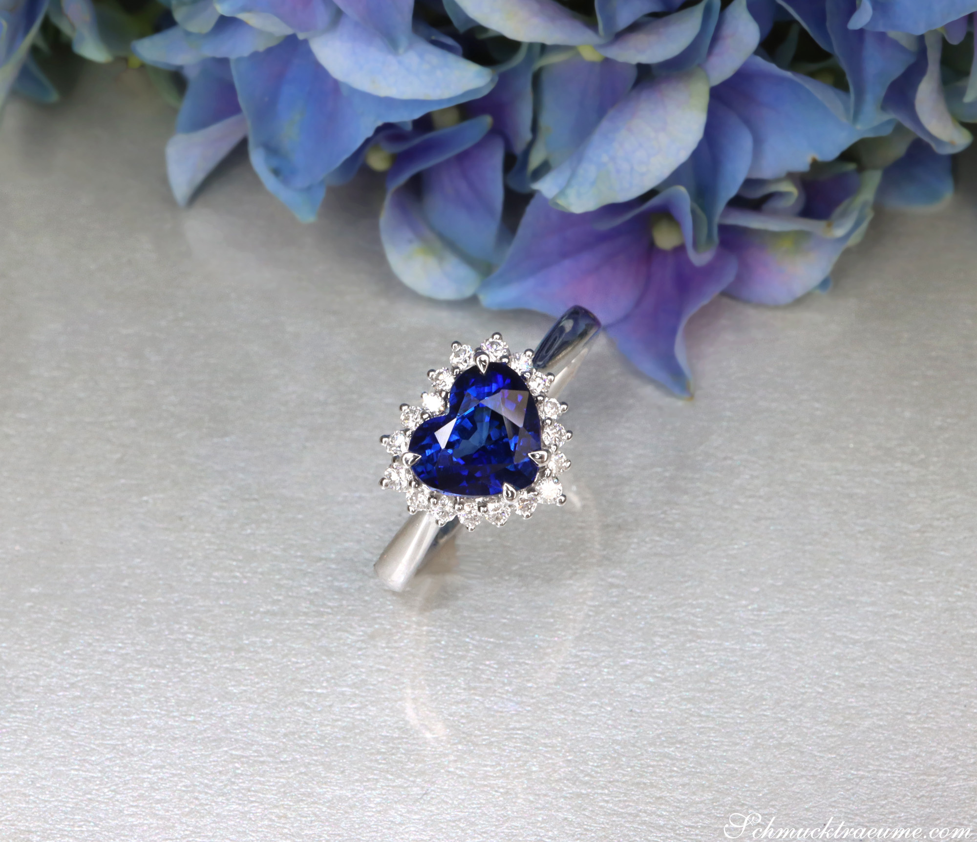 Herzring mit Saphir und Brillanten auf Blütenhintergrund
