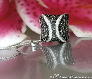 Schwarz-diamanten Anhänger im Rauten-Design, getragen auf Rosenblüte, Detailaufnahme.