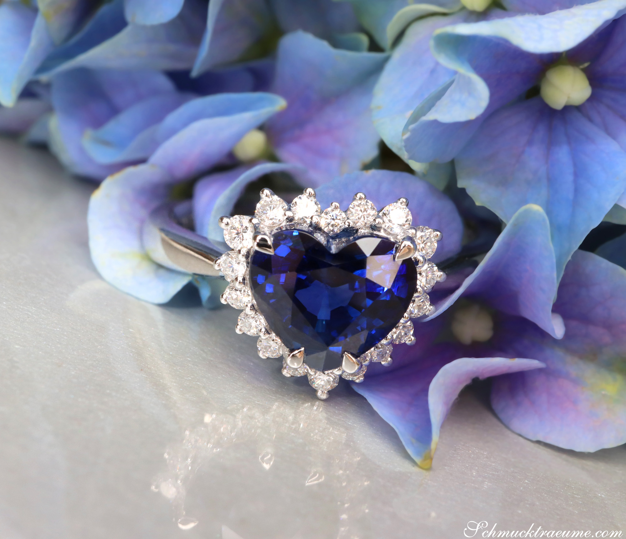 Herzform-Saphir-Ring mit Brillanten, Detailaufnahme, Blüten im Hintergrund
