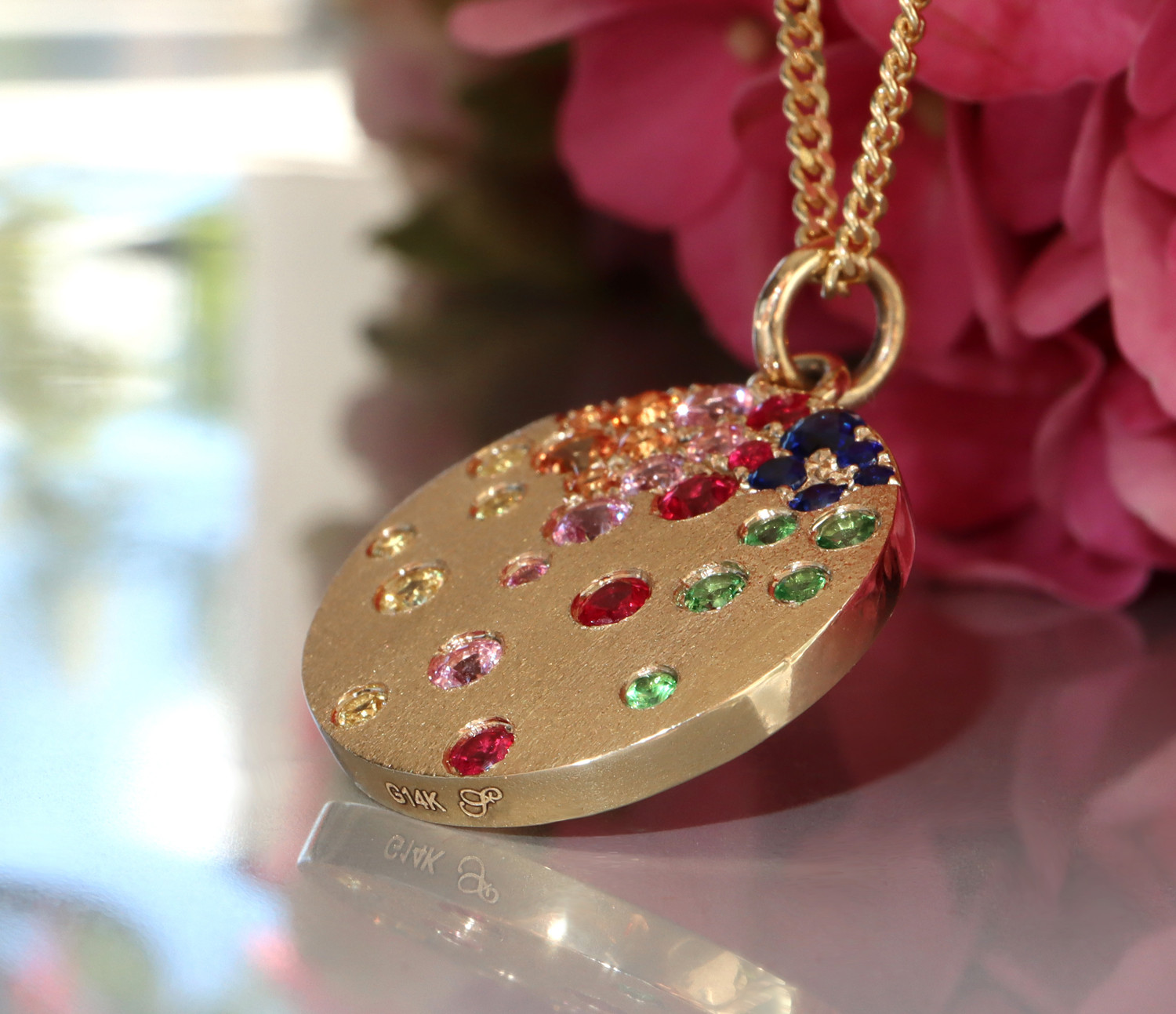 Goldene Medaillon-Halskette mit farbenfrohen Saphiren, Rubinen und Tsavorites, Detailaufnahme.