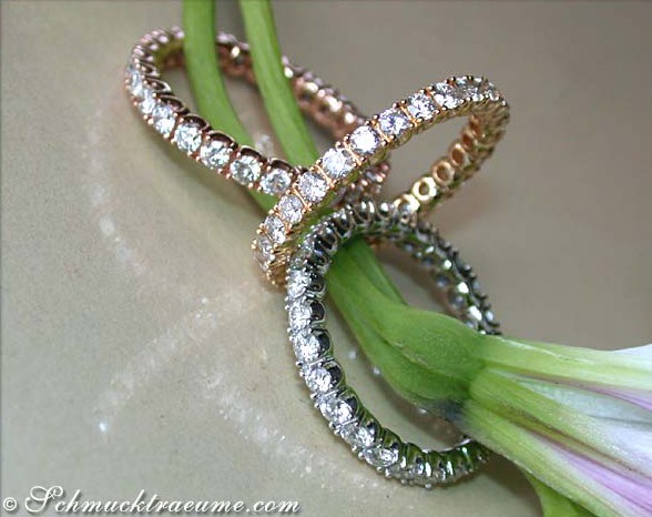 Erhabene Brillantenringe aus Weiß-, Rosé- & Gelbgold 585, elegant überkreuzt, mit Blütenblättern im Hintergrund