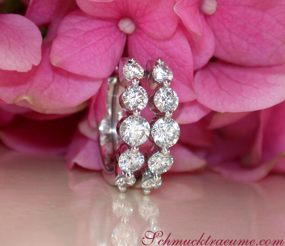 Detail der Diamantohrringe mit zehn steigenden Brillanten auf rosafarbenem Hintergrund