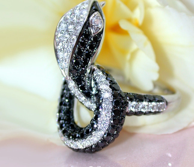 Schwarz-Weiß-Diamant-Schlangenring auf Rosenblüte, Detailaufnahme Schwarz-Weiß-Diamant-Schlangenring auf Rosenblüte, Detailaufnahme