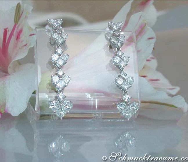Diamant-Ohrringe Herz-Design in Weißgold, elegant auf Blütenblättern präsentiert Diamant-Ohrringe Herz-Design in Weißgold, elegant auf Blütenblättern präsentiert