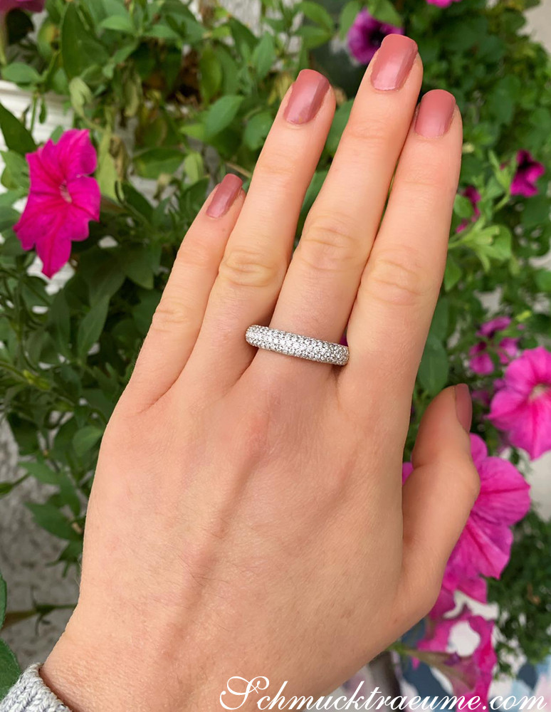 Weißgold-Diamant-Pavé-Ring getragen vor Blumen, Nagellack rosa.