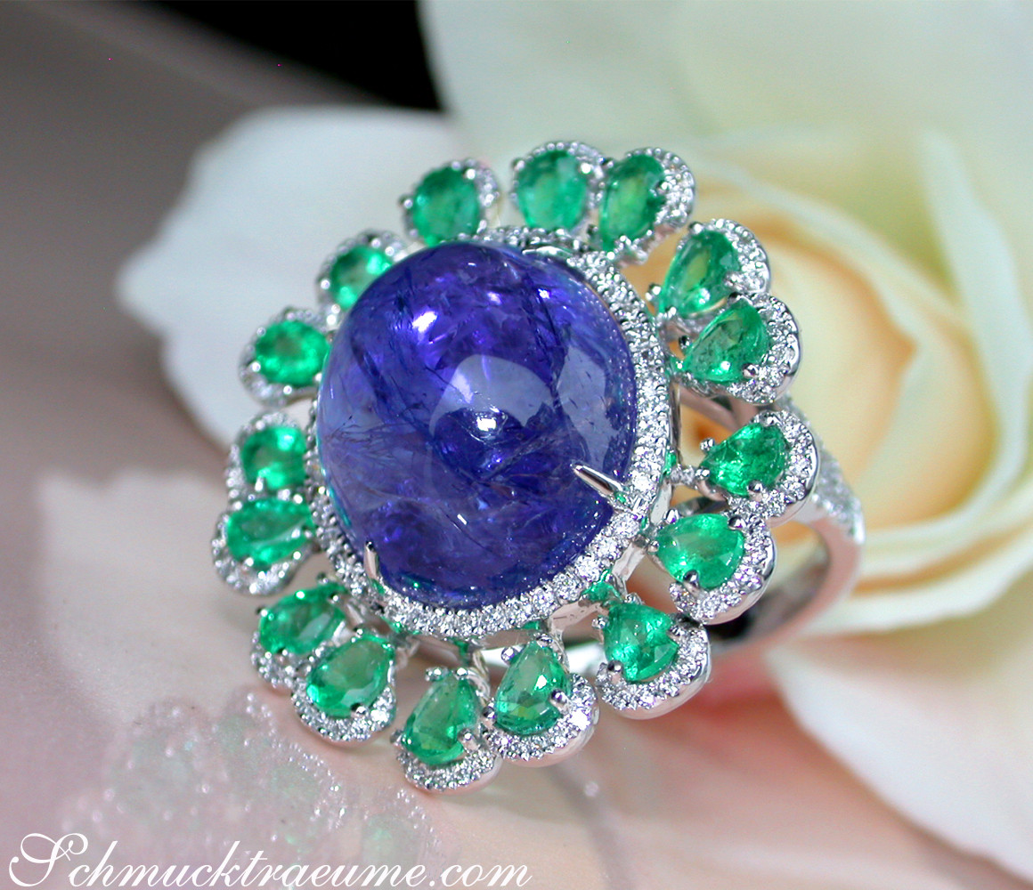 Opulenter Tansanit-Ring mit Smaragden und Brillanten, Detailaufnahme, Weißgold 750, Rosenblüte im Hintergrund.