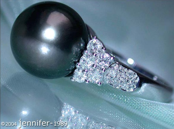 Tahitiperlen-Ring mit Brillanten in Weißgold, detailreiches Design, auf Netzunterlage.