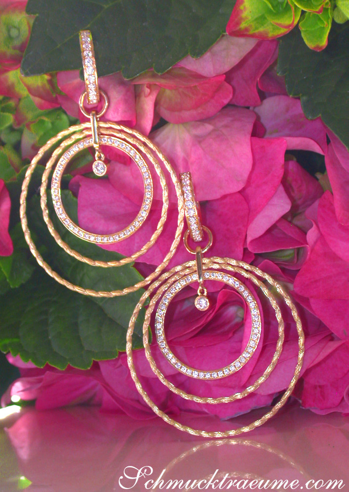 Kreisförmige Goldohrringe mit Brillanten auf Blumenhintergrund