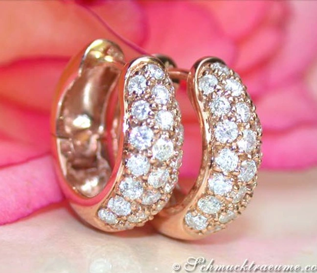 Detailansicht von roségoldenen Creolen mit Brillanten vor rosa Blüte Detailansicht von roségoldenen Creolen mit Brillanten vor rosa Blüte