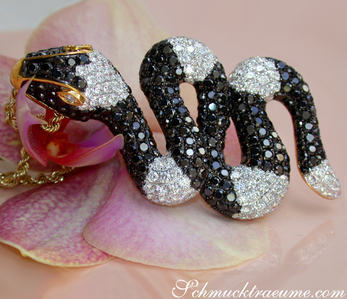 Schlangenanhänger mit schwarzen & weißen Diamanten, goldene Kette, auf Orchideenblüte liegend