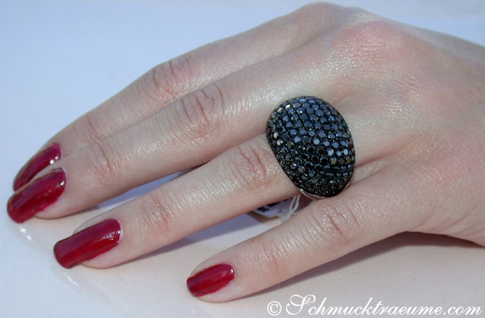 Schwarz-diamantierte Dome-Ring auf Hand mit roten Nagellack, Detailaufnahme.