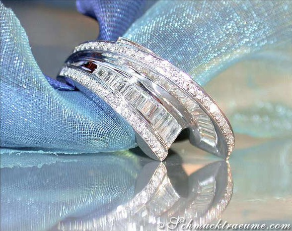 Diamantring in Weißgold 750 mit Baguette-Diamanten, Detailaufnahme auf blauem Stoff, glänzende Perlenverzierungen