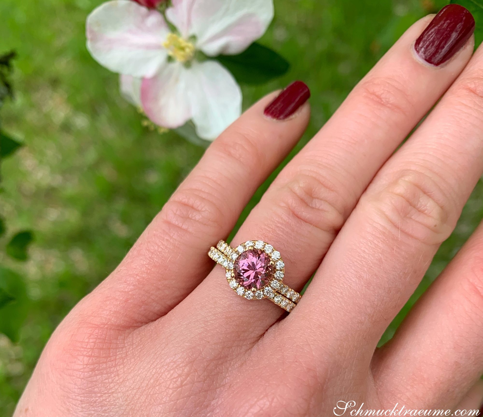 Rosa Granat-Ring mit Brillanten auf grünem Hintergrund, Nahaufnahme.