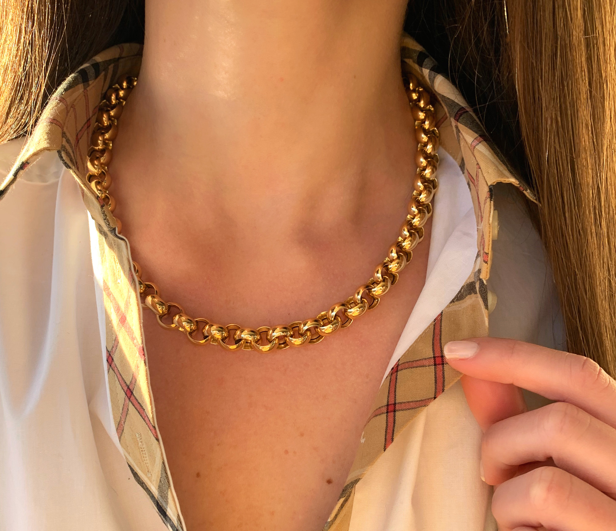 Goldene Halskette mit dicker Kette um den Hals, Detailaufnahme bei Tageslicht.