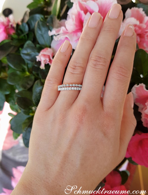 Fingerdetail mit Diamanten-Bandring auf Blumenhintergrund