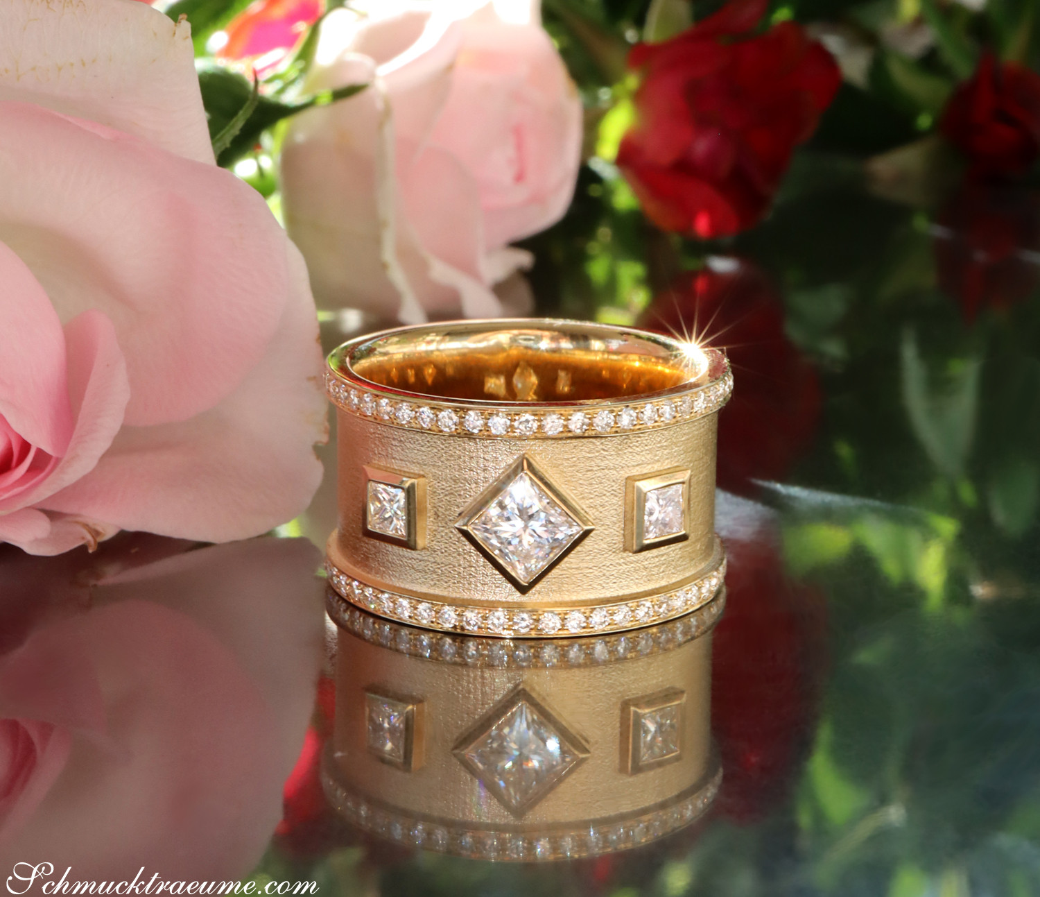 Goldener Diamantring mit Princess-Diamanten und Diamantbesatz, umgeben von Rosenblüten