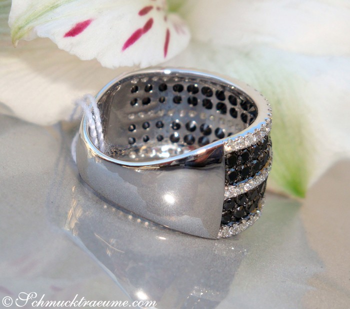 Schwarz-weißer Diamant-Ring mit Perlen auf Marmor mit Blume im Hintergrund