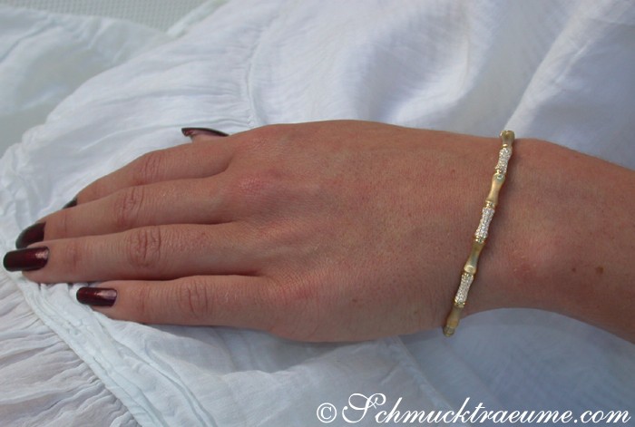 Edler Diamantenarmreif im Bambus-Design auf gesteppter Hand mit lackierten Nägeln