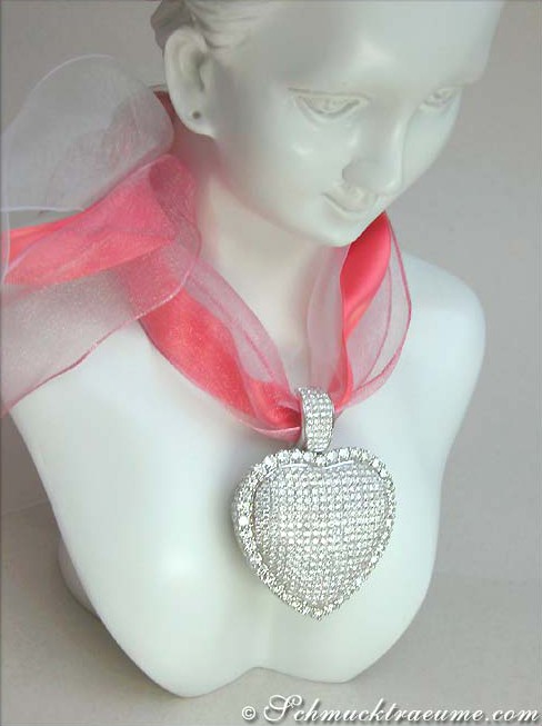 Silberner Herzanhänger mit Strasssteinen auf weißem Mannequin, rosa Schleife