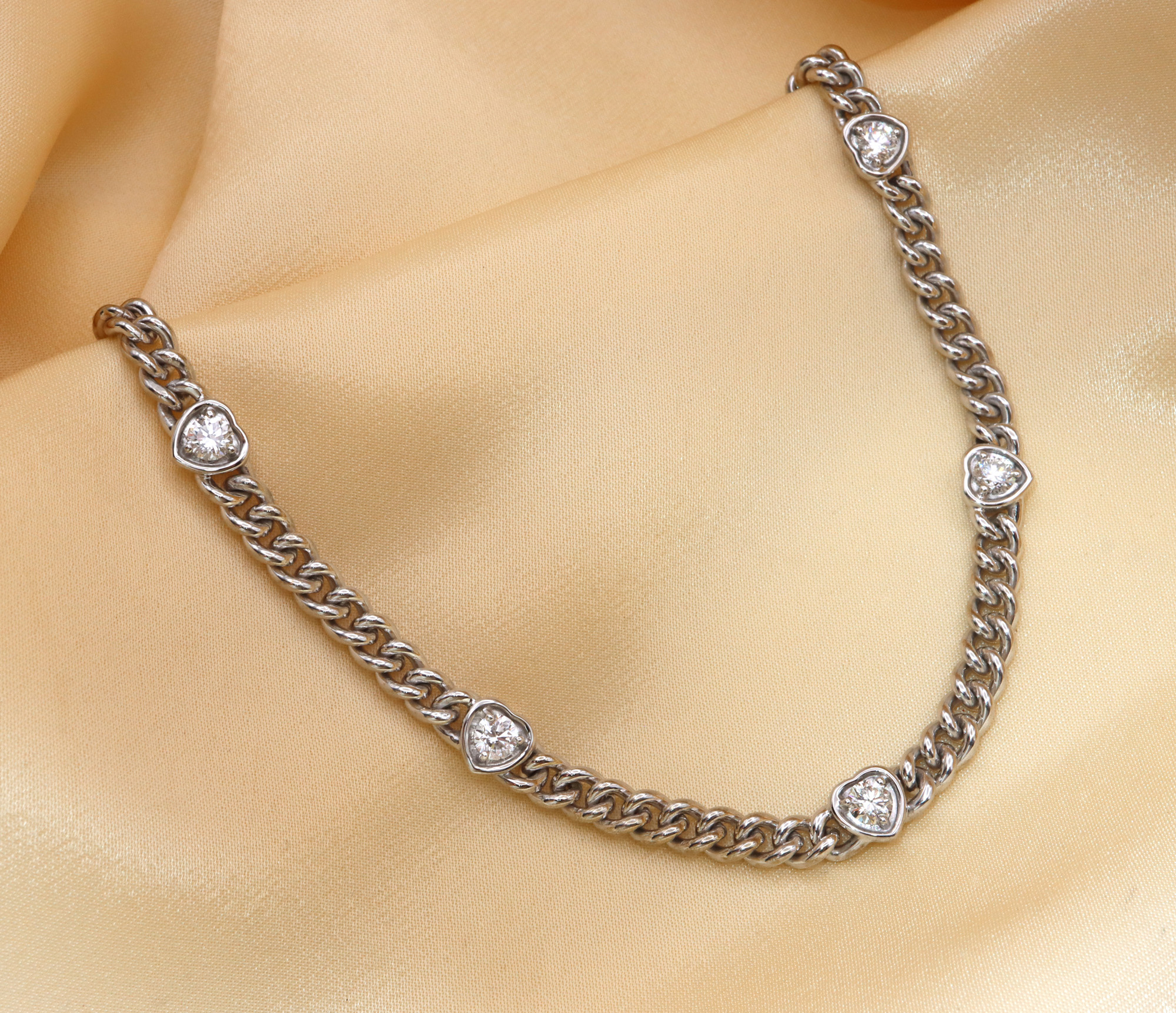 Silbernes Panzerarmband mit Herz-Brillanten, detailreich auf glänzendem Stoff.