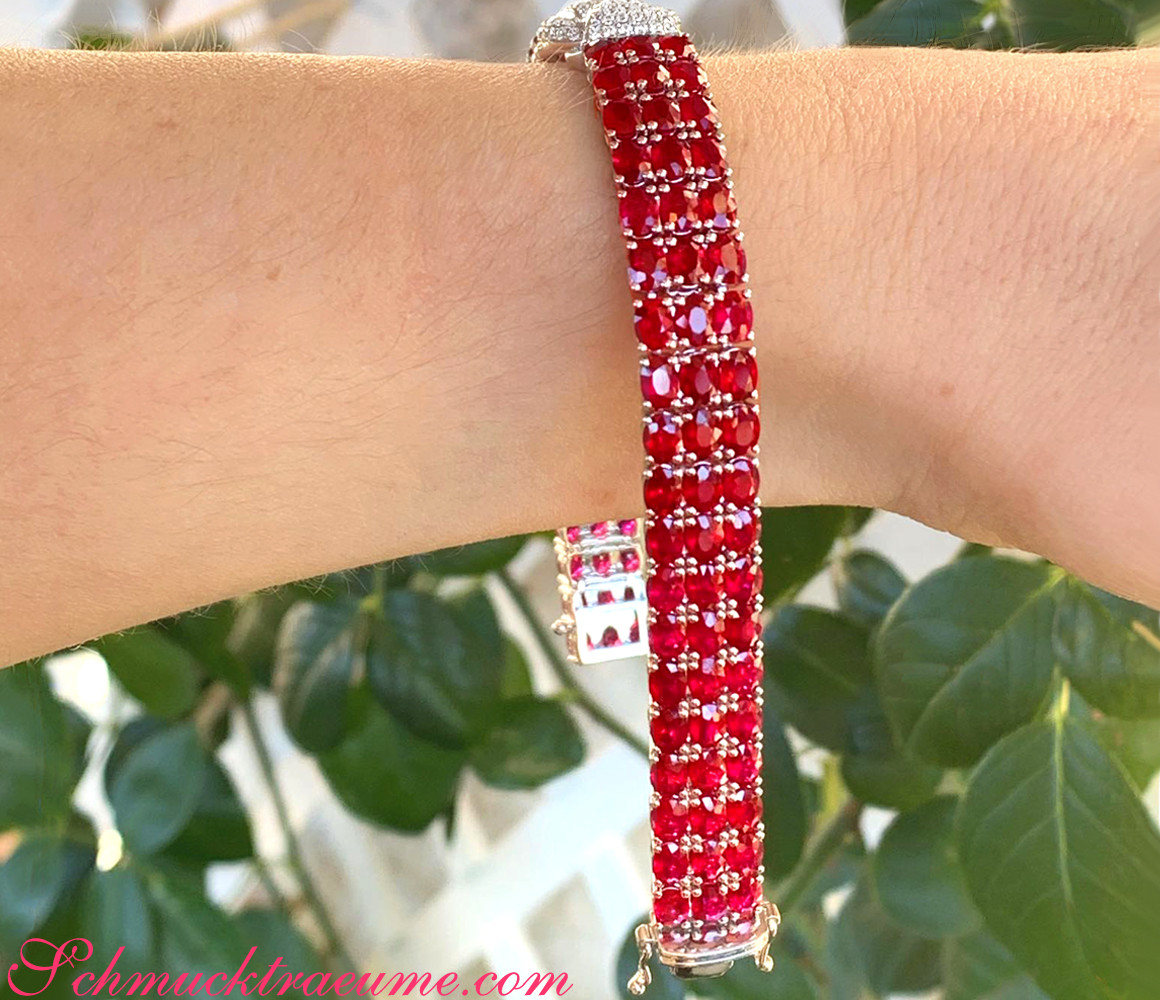 Rubinarmband mit Brillanten auf der Hand, Detailaufnahme, grüne Pflanzen im Hintergrund