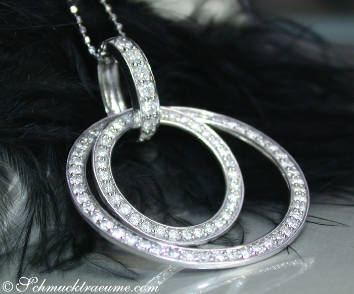 Schwarz-weißer Clip-Anhänger mit Diamanten, glänzende Details, elegant auf Federhintergrund.