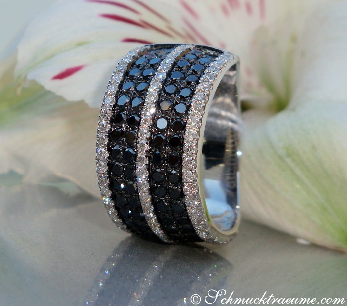 Weißgoldener Ring mit schwarzen und weißen Diamanten, Detailansicht, elegant auf Blume platziert.