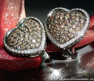 Herz-Ohrringe aus Weißgold 585, verziert mit braunen und weißen Brillanten, auf rotem Samt liegend.