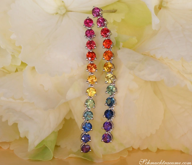Weißgold-Ohrgehänge mit Regenbogen-Saphiren, detailreich, elegant, auf Blüte abgebildet Weißgold-Ohrgehänge mit Regenbogen-Saphiren, detailreich, elegant, auf Blüte abgebildet