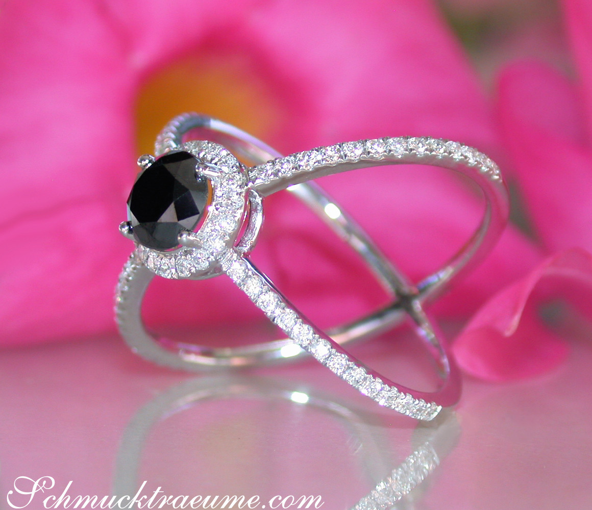 Schwarzer Diamant Solitär Ring mit Diamantbesatz, vor rosa Blume.