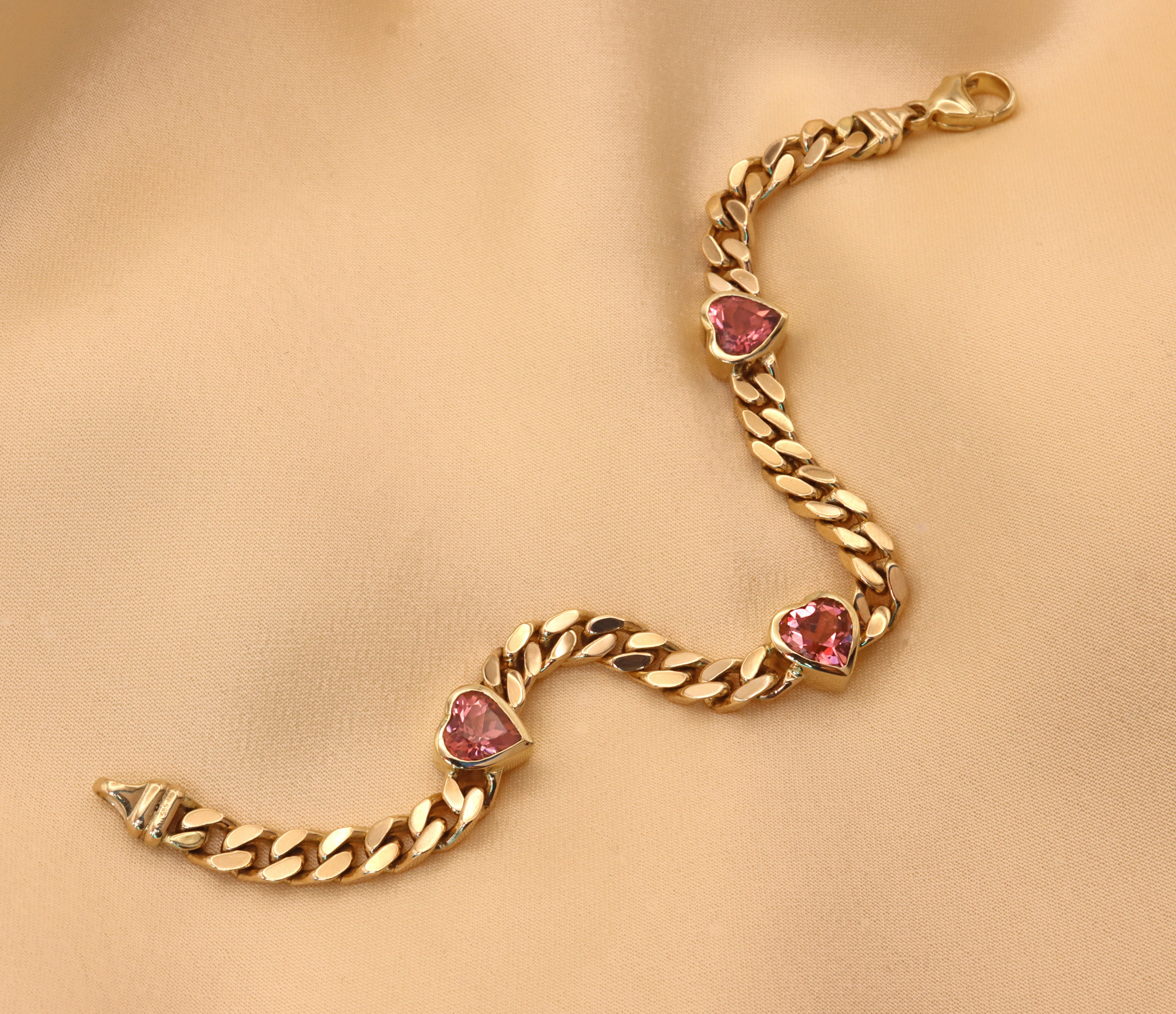 Goldene Panzerarmband mit rosa Turmalinherzen, detailreich, elegant.