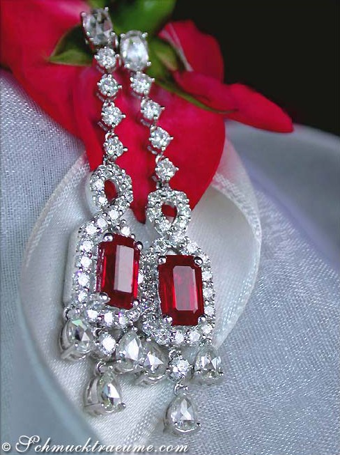 Detail der eleganten Burma-Rubin-Ohrgehänge mit Diamanten, auf weißem Stoff mit Blume im Hintergrund