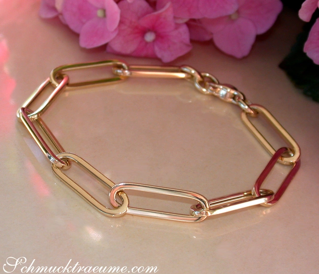 Gold-Papierclip-Armband in Gelbgold 585 mit modernen Linien und rosafarbenen Blüten im Hintergrund Gold-Papierclip-Armband in Gelbgold 585 mit modernen Linien und rosafarbenen Blüten im Hintergrund