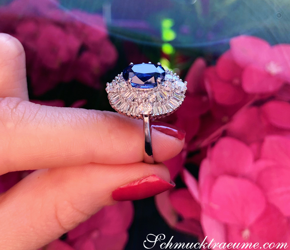 Blauer Saphir-Ring mit Diamanten, Detailaufnahme, im Handballen getragen, vor rosa Blüten