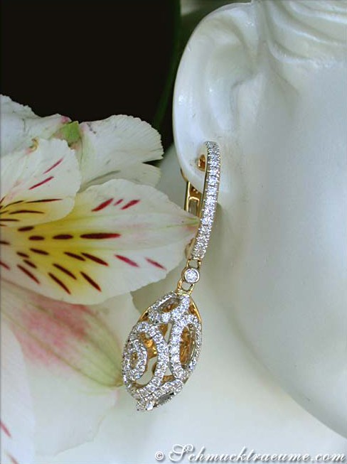 Weißgold-Ohrhänger mit Diamanten, detailreiches Design, getragen auf Porzellanmodell, Blüte im Hintergrund