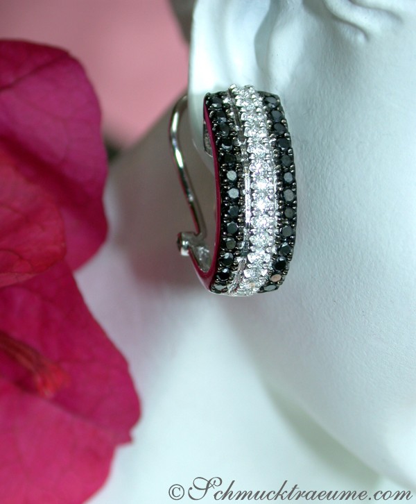 Ohrringe mit schwarzen und weißen Diamanten auf weißem Mannequin, Detailaufnahme.