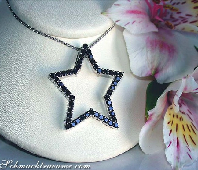 Schwarzer Diamantenstern-Anhänger auf Kette, Detailaufnahme, Blüten im Hintergrund. Schwarzer Diamantenstern-Anhänger auf Kette, Detailaufnahme, Blüten im Hintergrund.