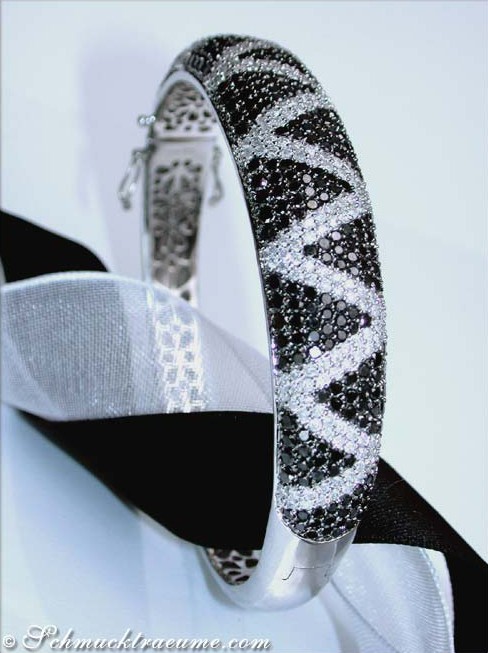 Schwarz-weißer Diamant-Armreif im Zig-Zag-Design auf weißem Stoff, Detailaufnahme