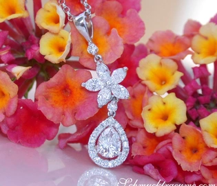 Diamant-Tropfen-Anhänger mit Marquise-Diamanten in Weißgold, detailreich, vor Blütenhintergrund.