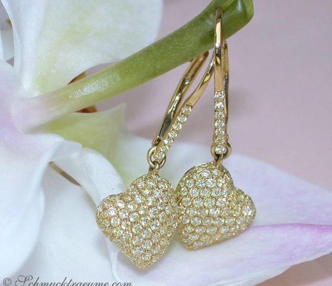 Gelbgold Herz Ohrringe mit Diamanten auf Orchidee, elegante Details, natürliche Hintergrundbeleuchtung. Gelbgold Herz Ohrringe mit Diamanten auf Orchidee, elegante Details, natürliche Hintergrundbeleuchtung.
